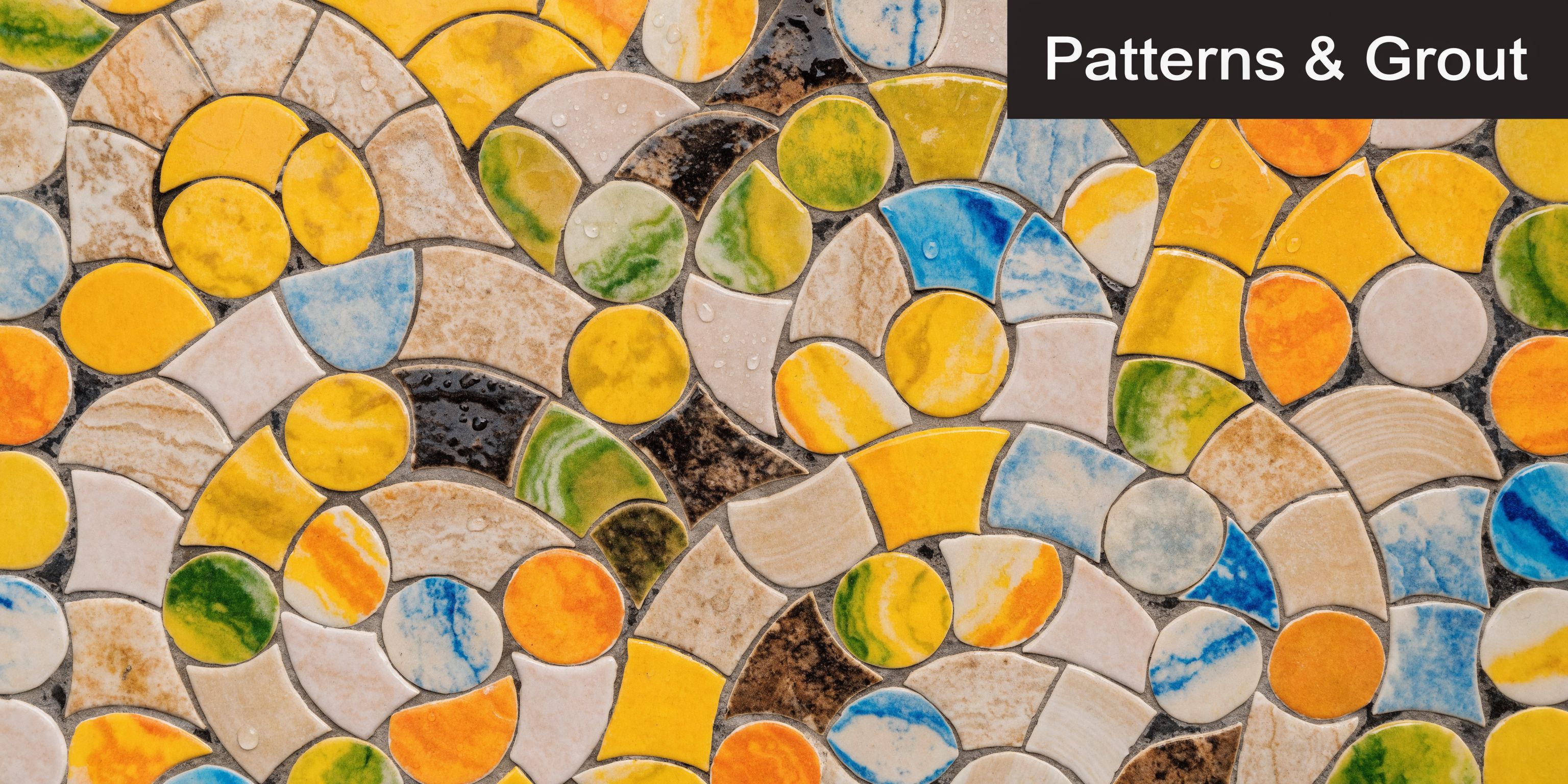 A colorful mosaic pattern featuring irregular ceramic tiles in shades of yellow, blue, green, and beige.