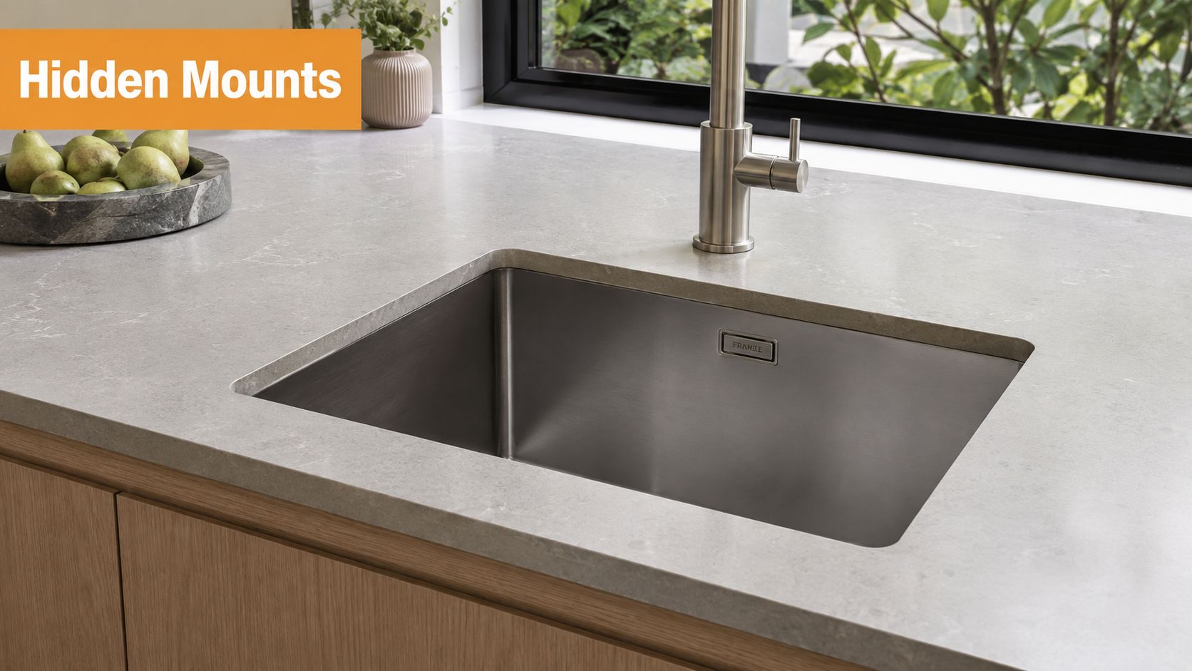 A modern kitchen stainless steel undermount sink set into a light grey marble countertop with a faucet.