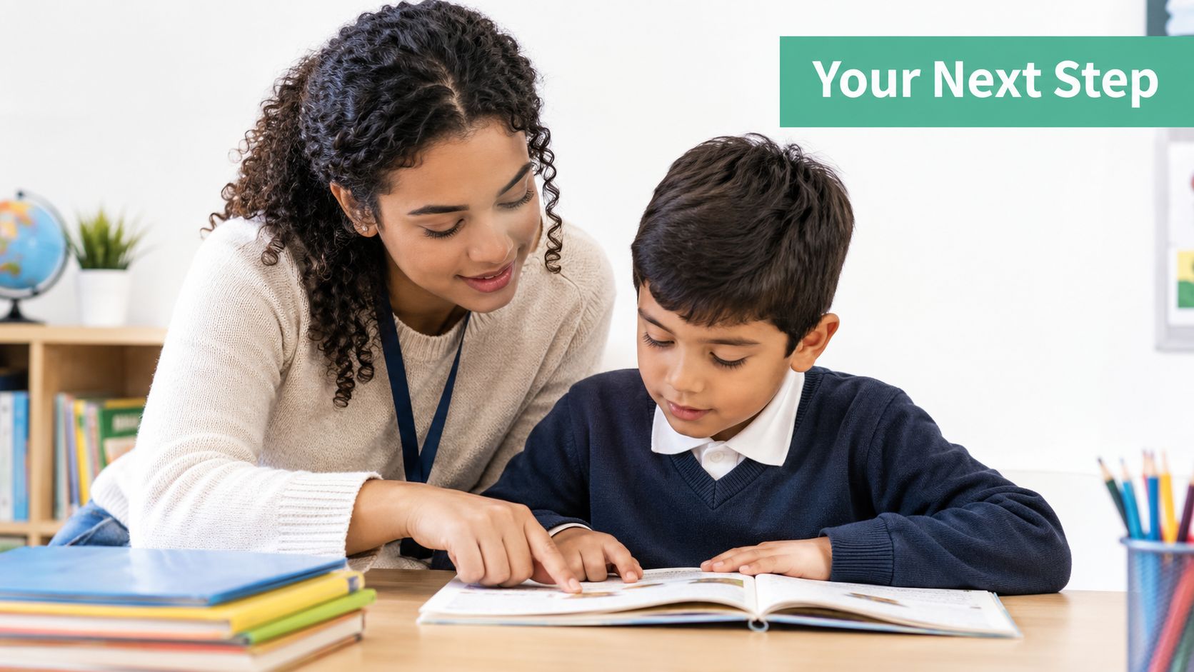 A female teacher assisting a young male student with his reading in a bright classroom setting.