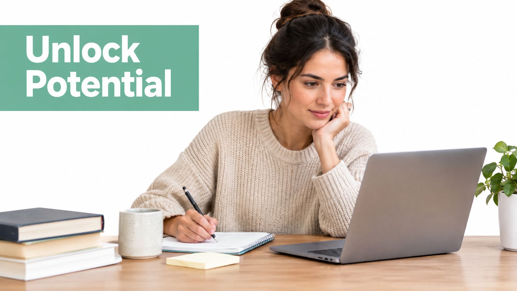 A woman studying while using a laptop and writing in a notebook at her wooden desk.