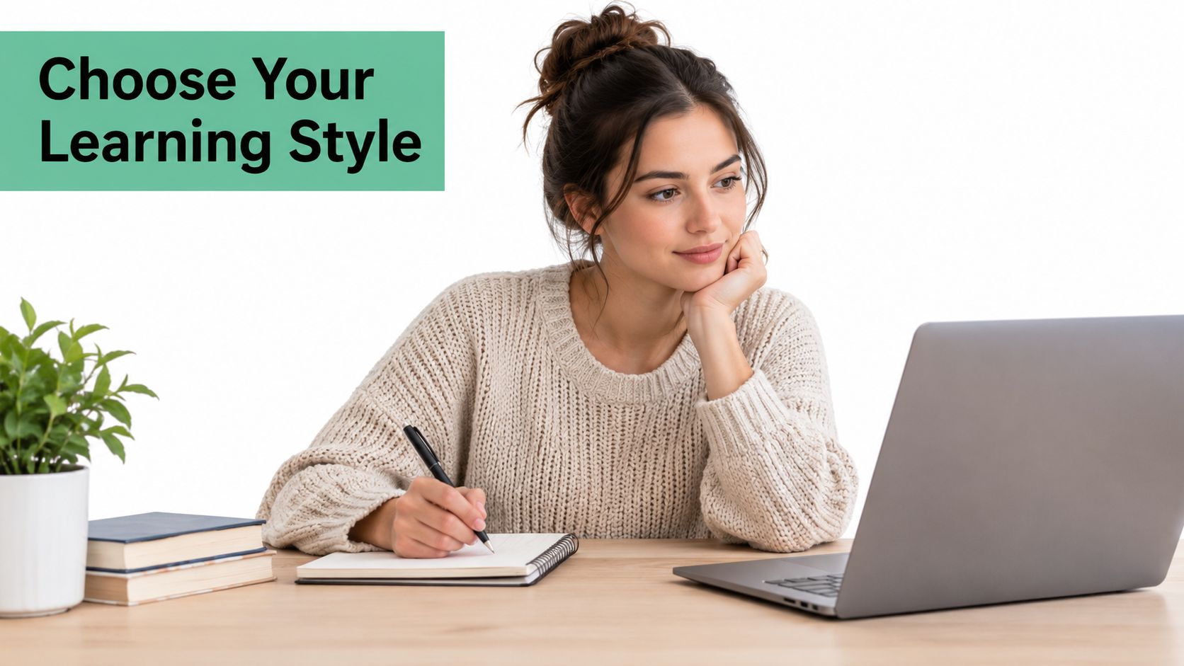 A young woman wearing a sweater writing in a notebook while looking at a laptop computer.