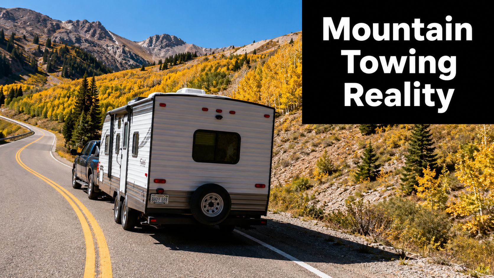 A truck towing a white travel trailer on a winding road through scenic mountains in autumn.