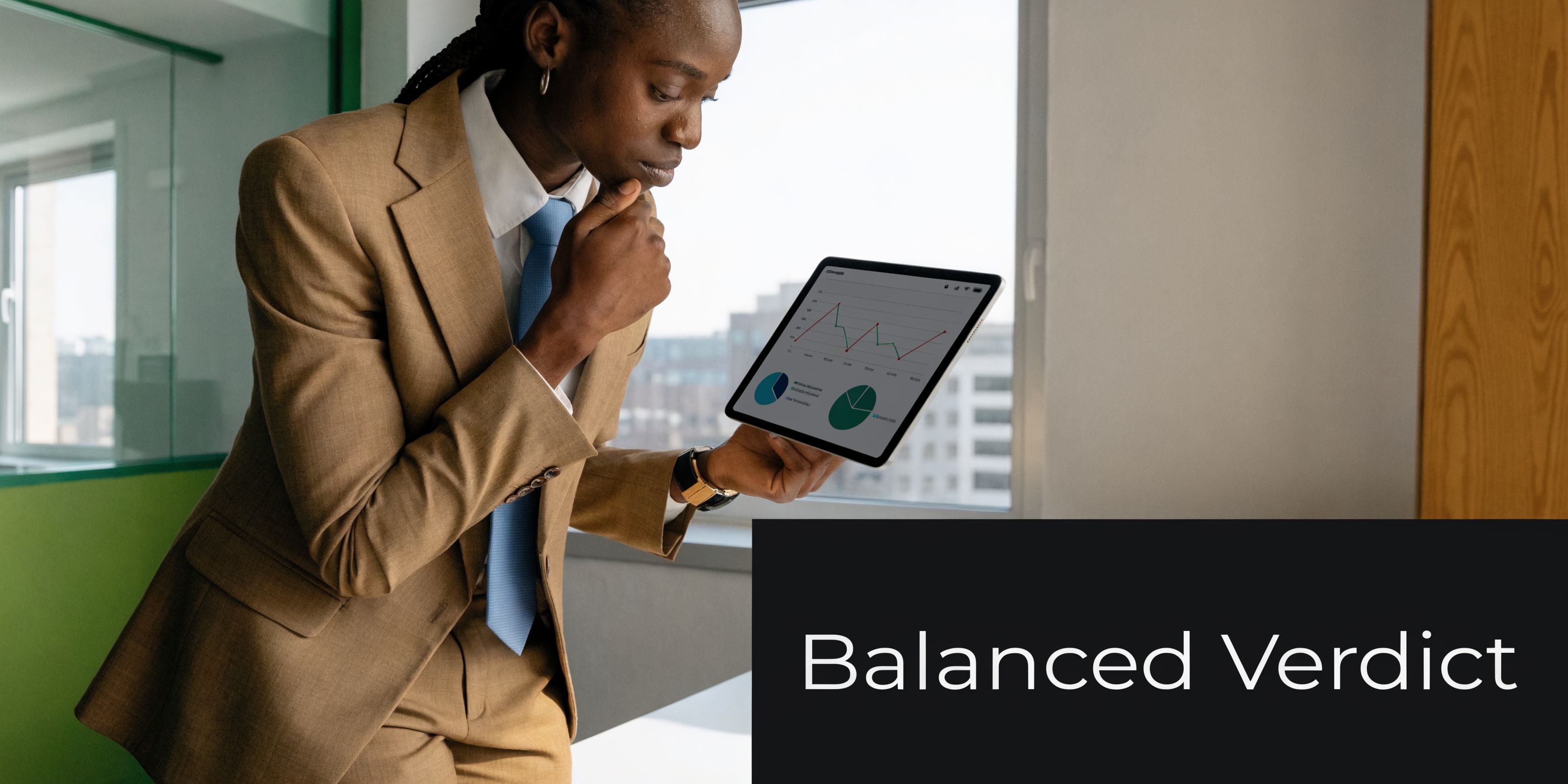 A professional woman in a tan suit analyzing financial charts on a tablet in an office.