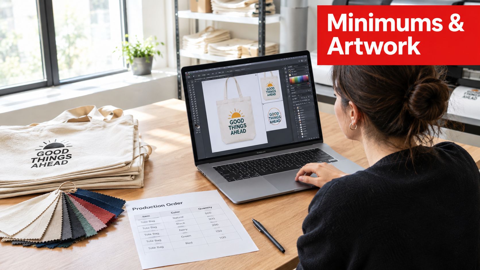 A designer works on custom tote bag branding on a laptop next to fabric samples and orders.