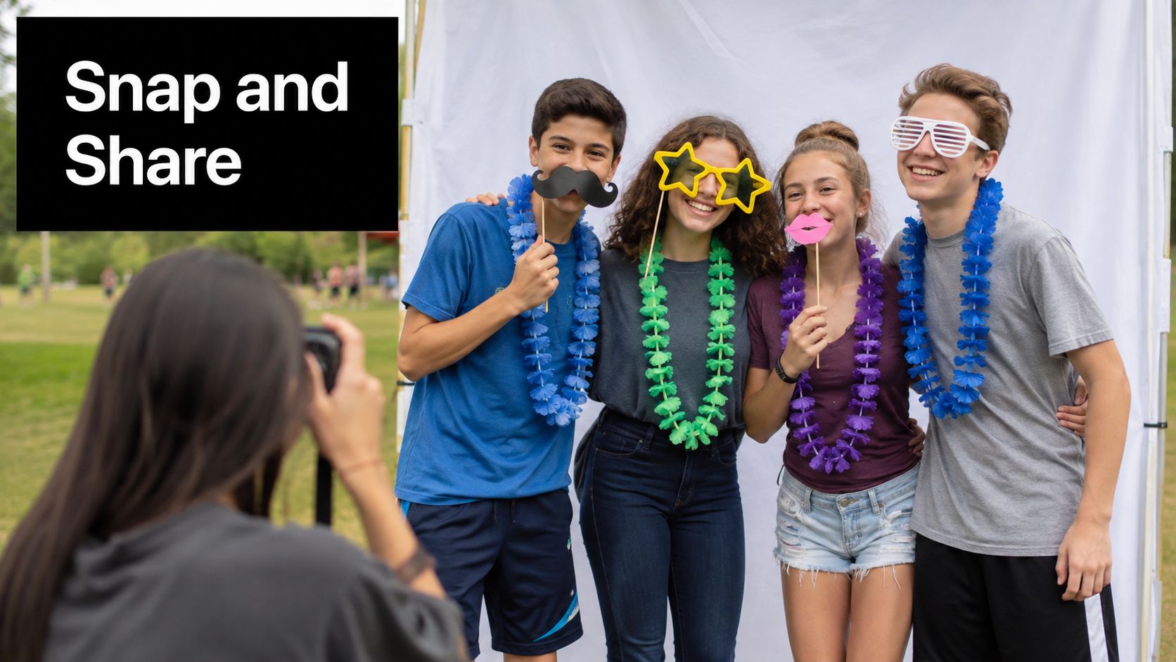 A group of teenagers wearing party props and leis pose for a photo at a field event.