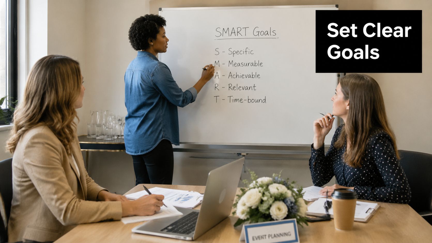 A professional woman writing SMART goals on a whiteboard while two colleagues participate in a planning meeting.