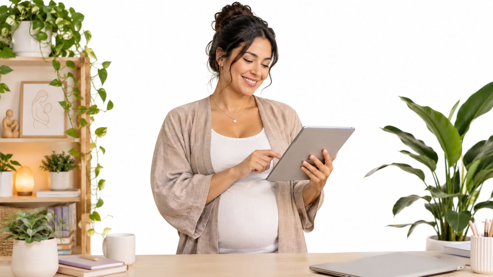 A smiling pregnant woman standing at a desk while looking at and using a digital tablet.