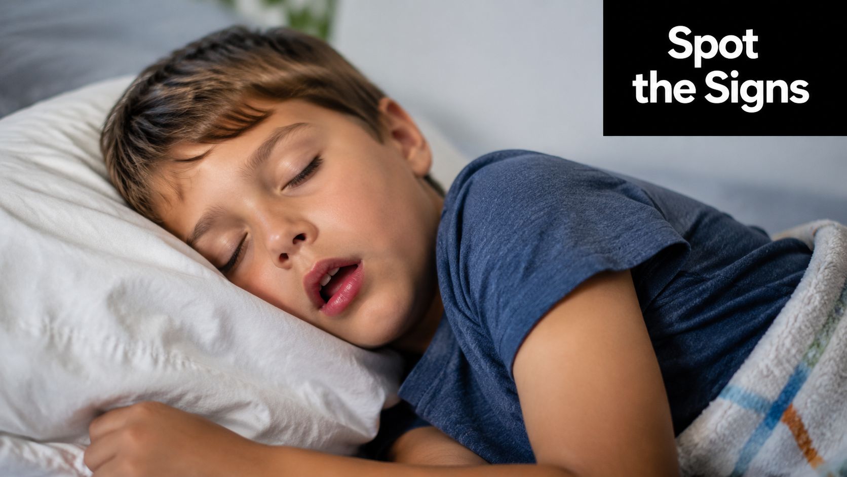 A young boy sleeping soundly with his mouth slightly open while resting on a white pillow.
