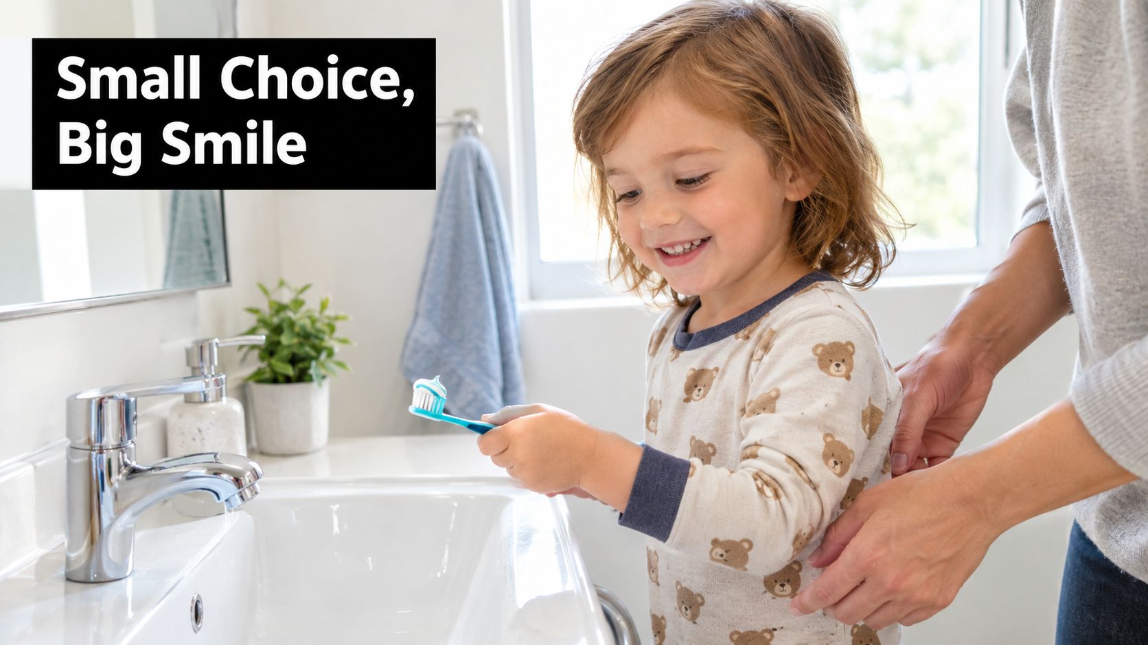 A young child smiling while holding a toothbrush with toothpaste, assisted by a parent in a bathroom.