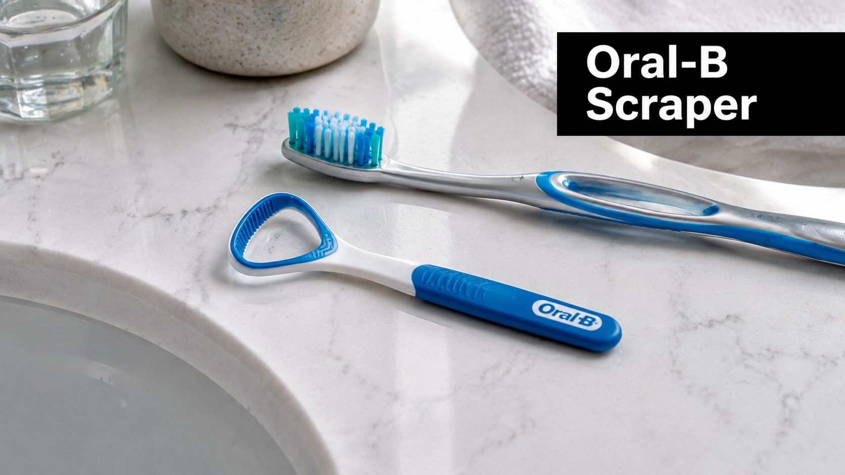 An Oral-B tongue scraper and a toothbrush resting on a clean white marble countertop next to a sink.