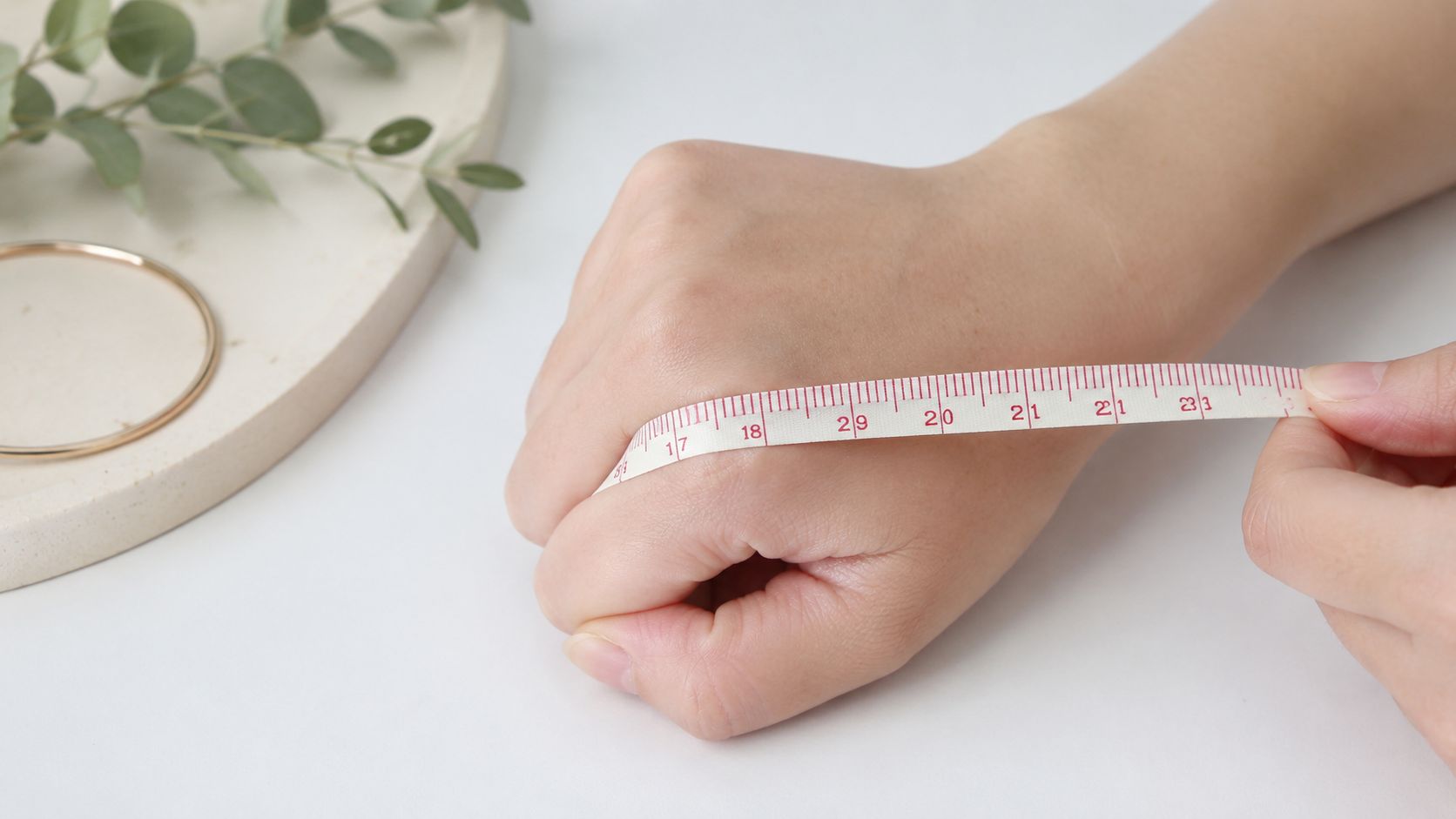 A close-up view of a person measuring their hand circumference with a tape for bracelet sizing.