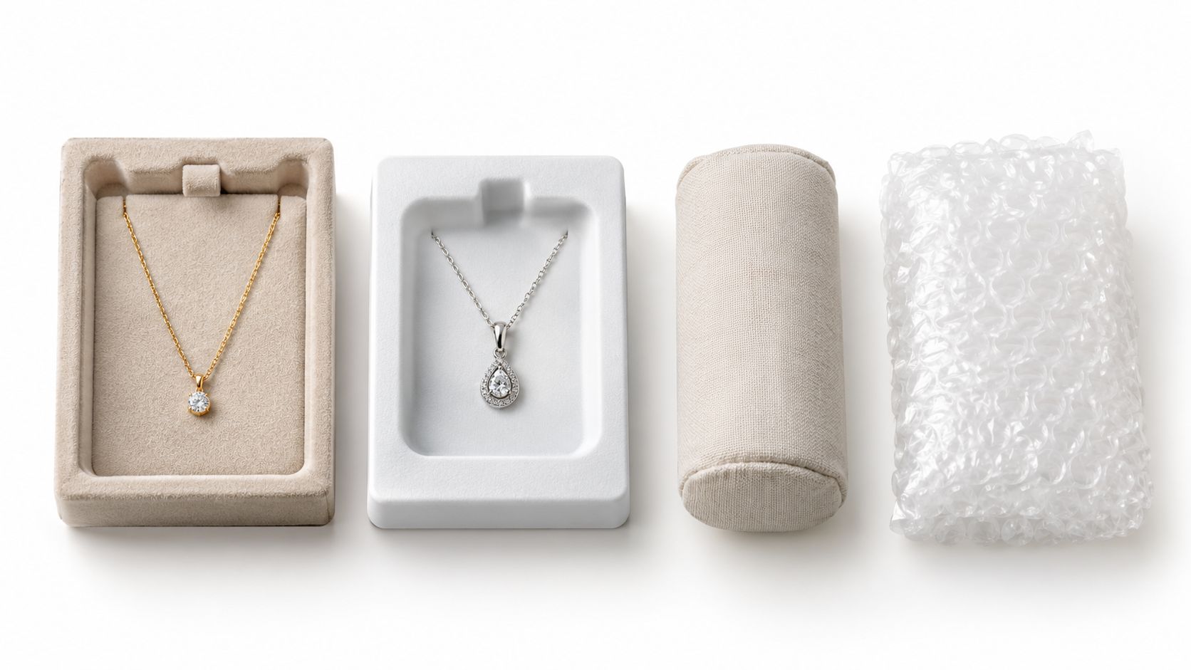 A high-angle studio shot showing two jewelry necklaces in packaging boxes, a velvet roll, and bubble wrap.