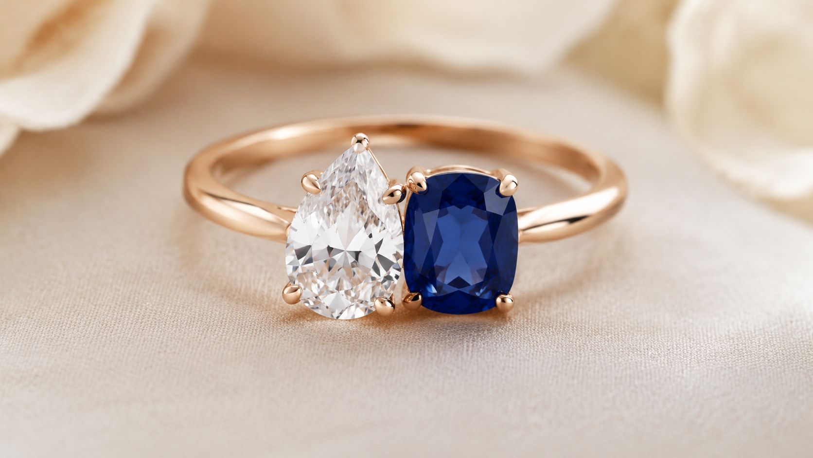 A luxurious two-stone engagement ring featuring a pear-cut diamond and a cushion-cut blue sapphire in gold.