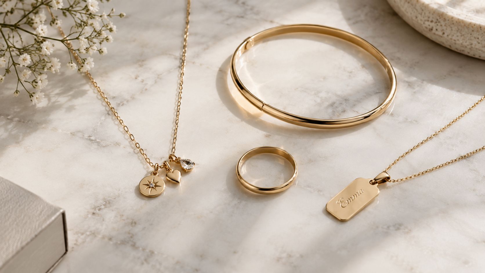 A collection of delicate 10k gold jewelry including necklaces, a bracelet, and a ring on marble.