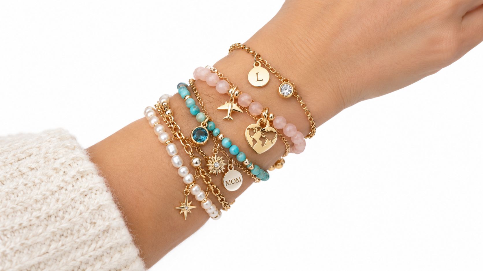 A close-up view of a wrist wearing a collection of five elegant gold and beaded layered bracelets.