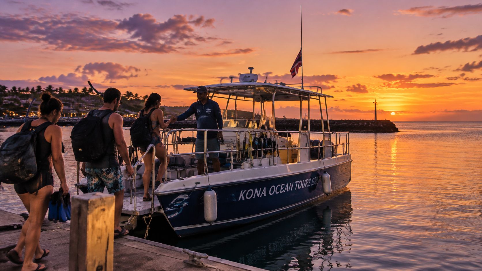 Passengers boarding a Kona Ocean Tours boat at sunset for a night manta ray dive excursion.