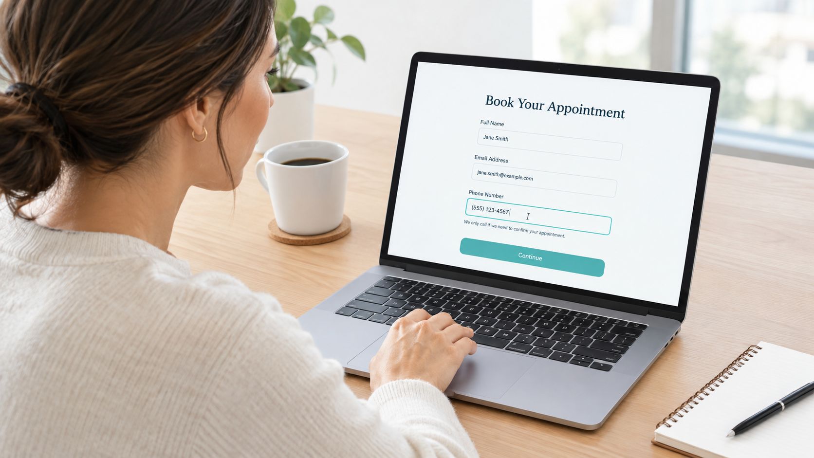 A woman filling out an online appointment booking form on her laptop screen while sitting at a desk.