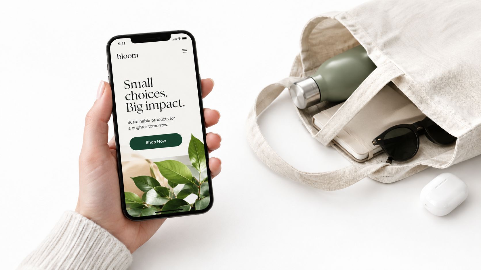 A hand holding a smartphone displaying a sustainable brand website alongside a canvas tote bag and accessories.