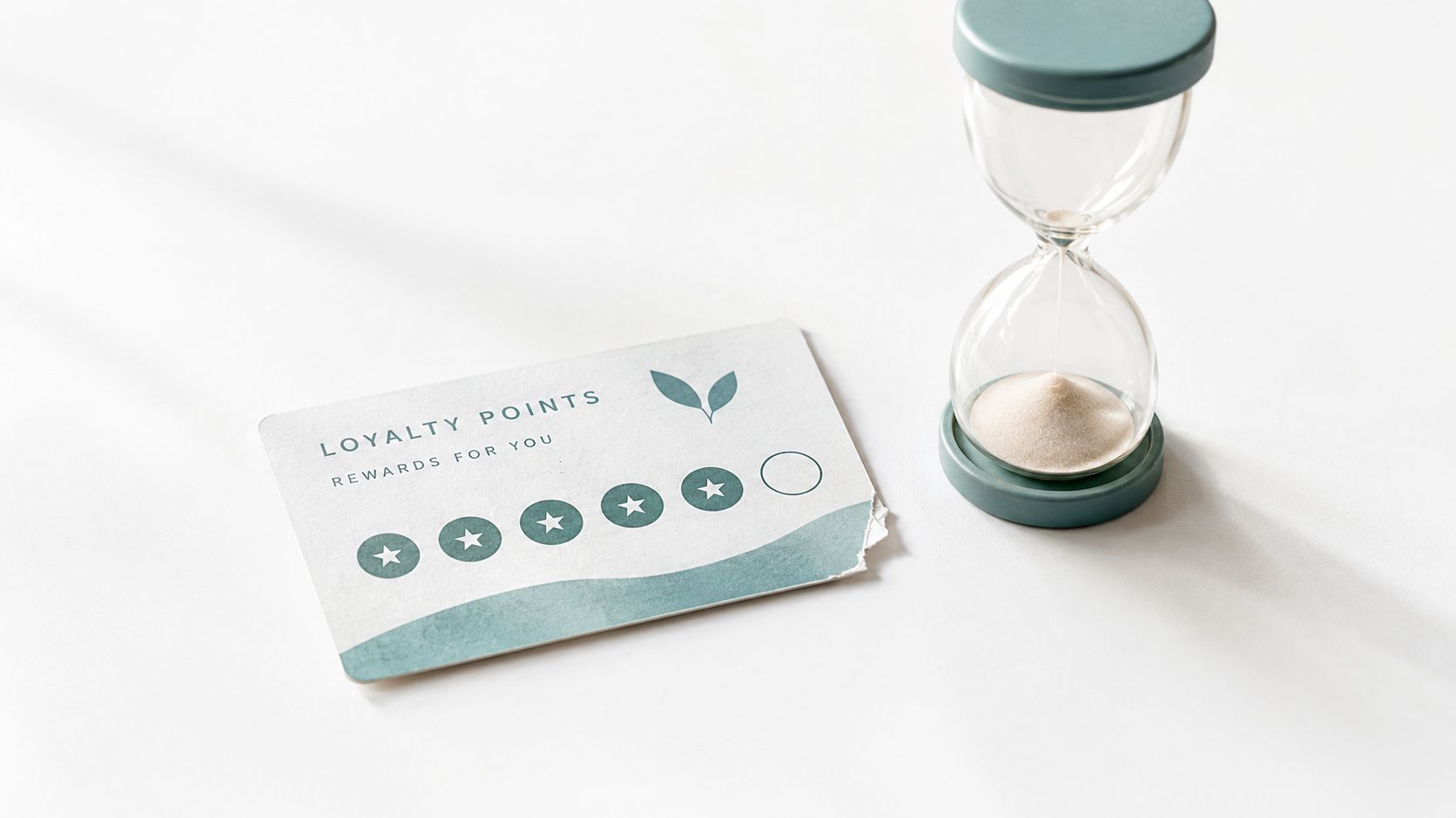 A loyalty points reward card with five stars and an hourglass sitting on a white surface.