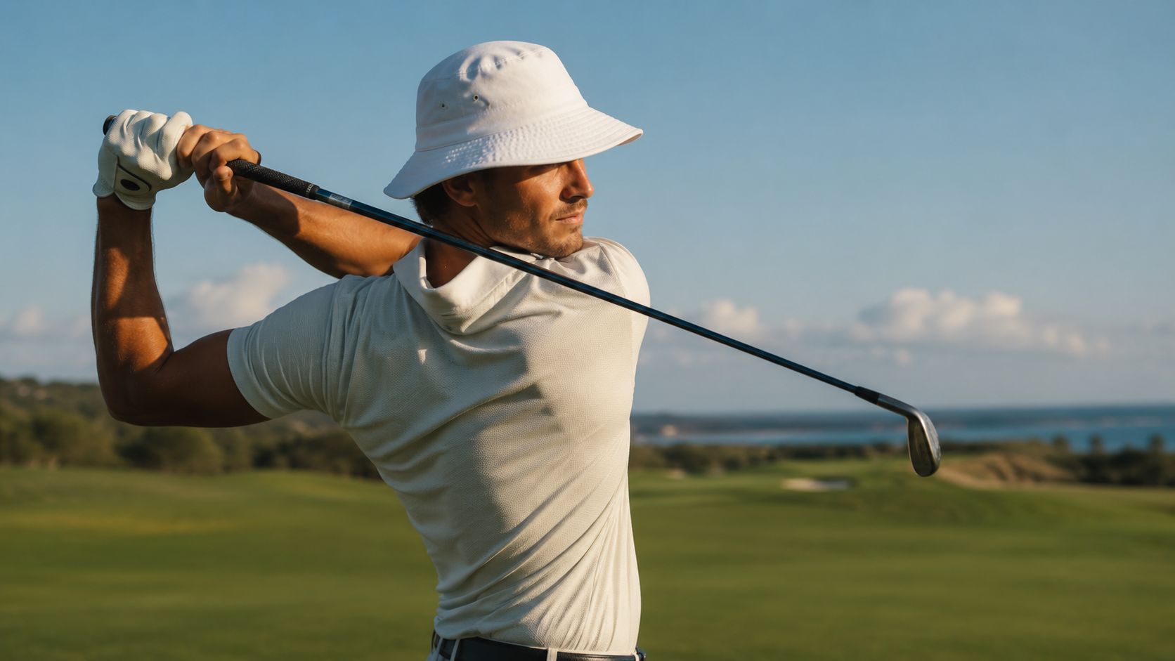 A male golfer in a white bucket hat performing a backswing on a sunny golf course.
