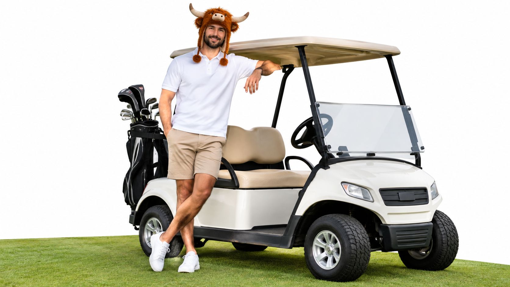 A smiling man wearing a highland cow hat leaning against a golf cart on a green lawn.