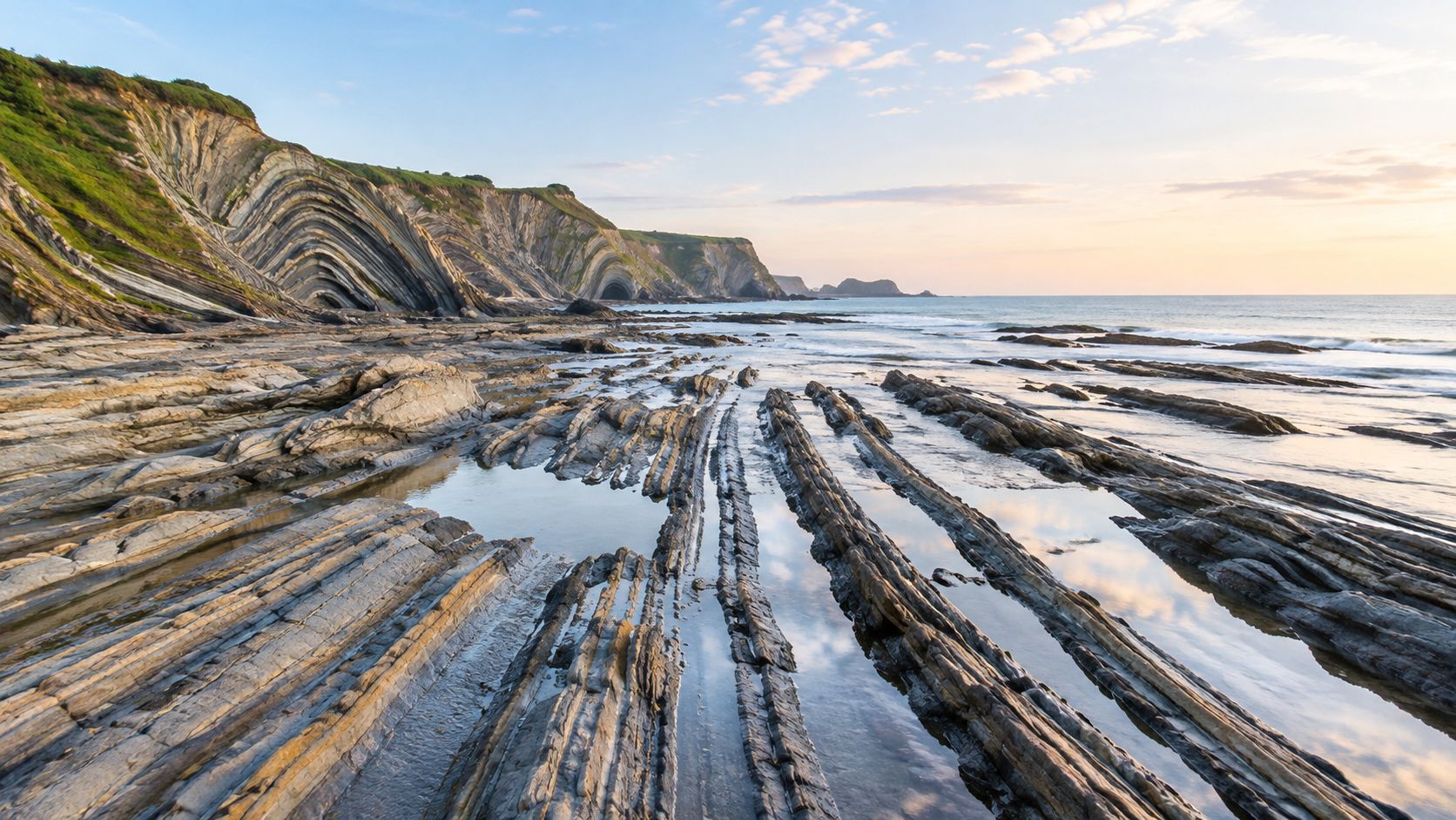 Stunning geological rock formations along the coastline of northern Spain during a calm and scenic sunset.
