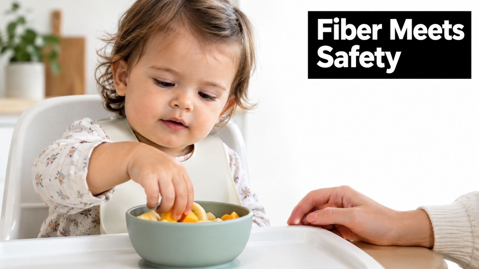 A toddler sitting in a high chair, picking healthy fruit pieces from a small green bowl.