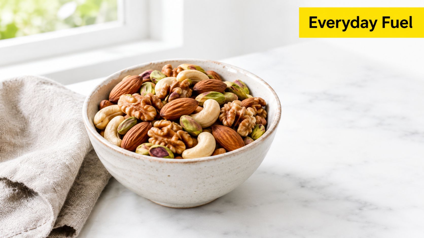 A ceramic bowl filled with a variety of healthy mixed nuts including cashews, walnuts, almonds, and pistachios.