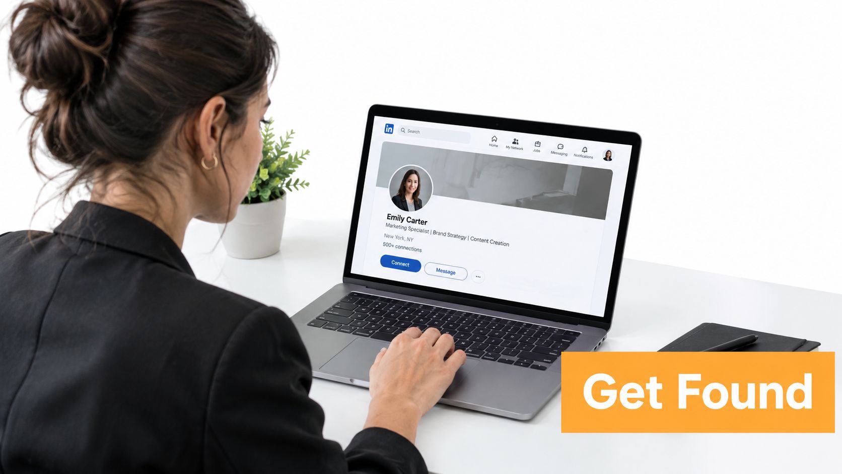 Uma mulher profissional usa um laptop para visualizar uma página de perfil do LinkedIn enquanto trabalha em sua mesa.
