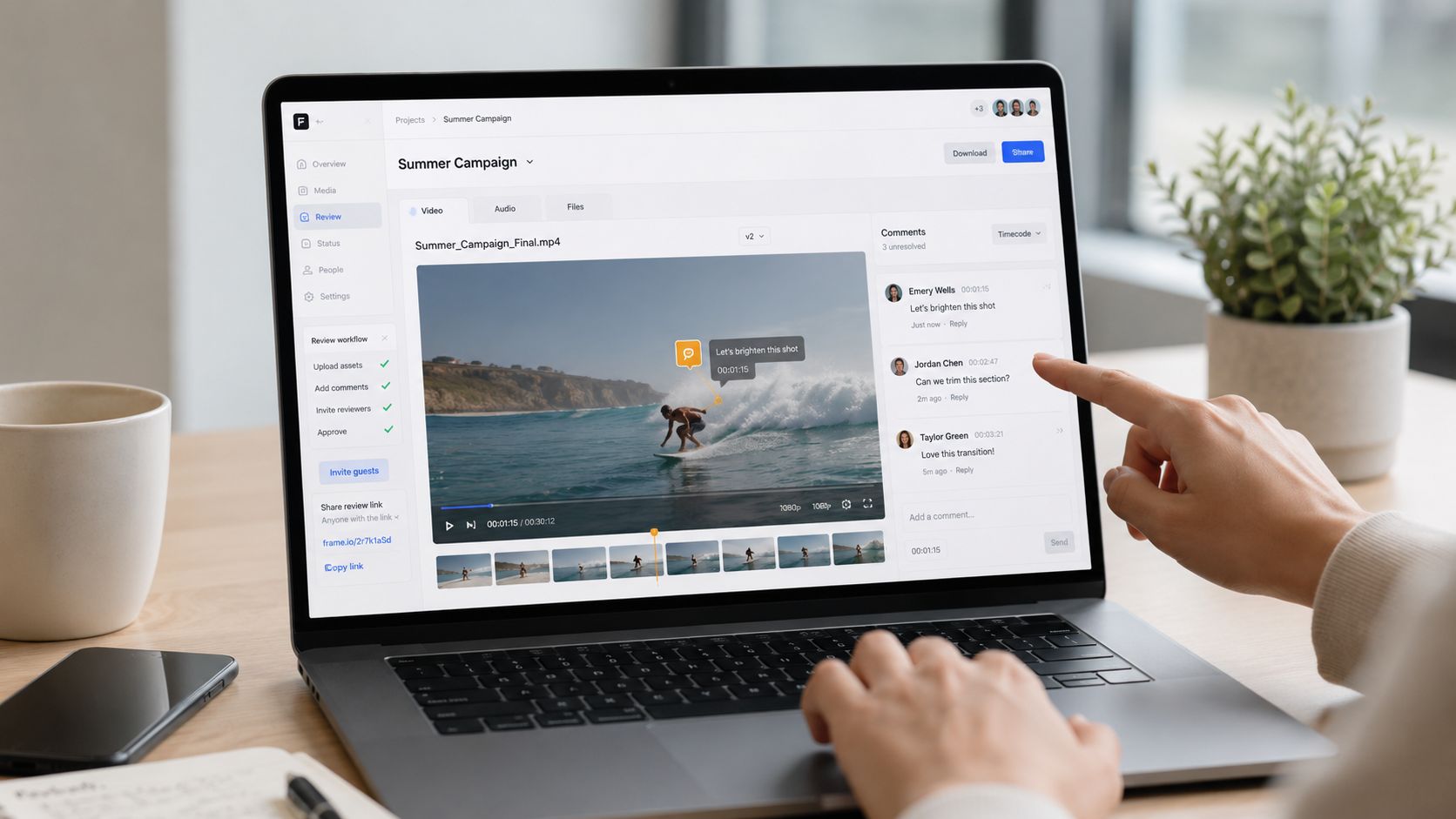 Ein Laptop zeigt eine Videobearbeitungsplattform mit Kommentaren, während eine Person auf den Bildschirm tippt.