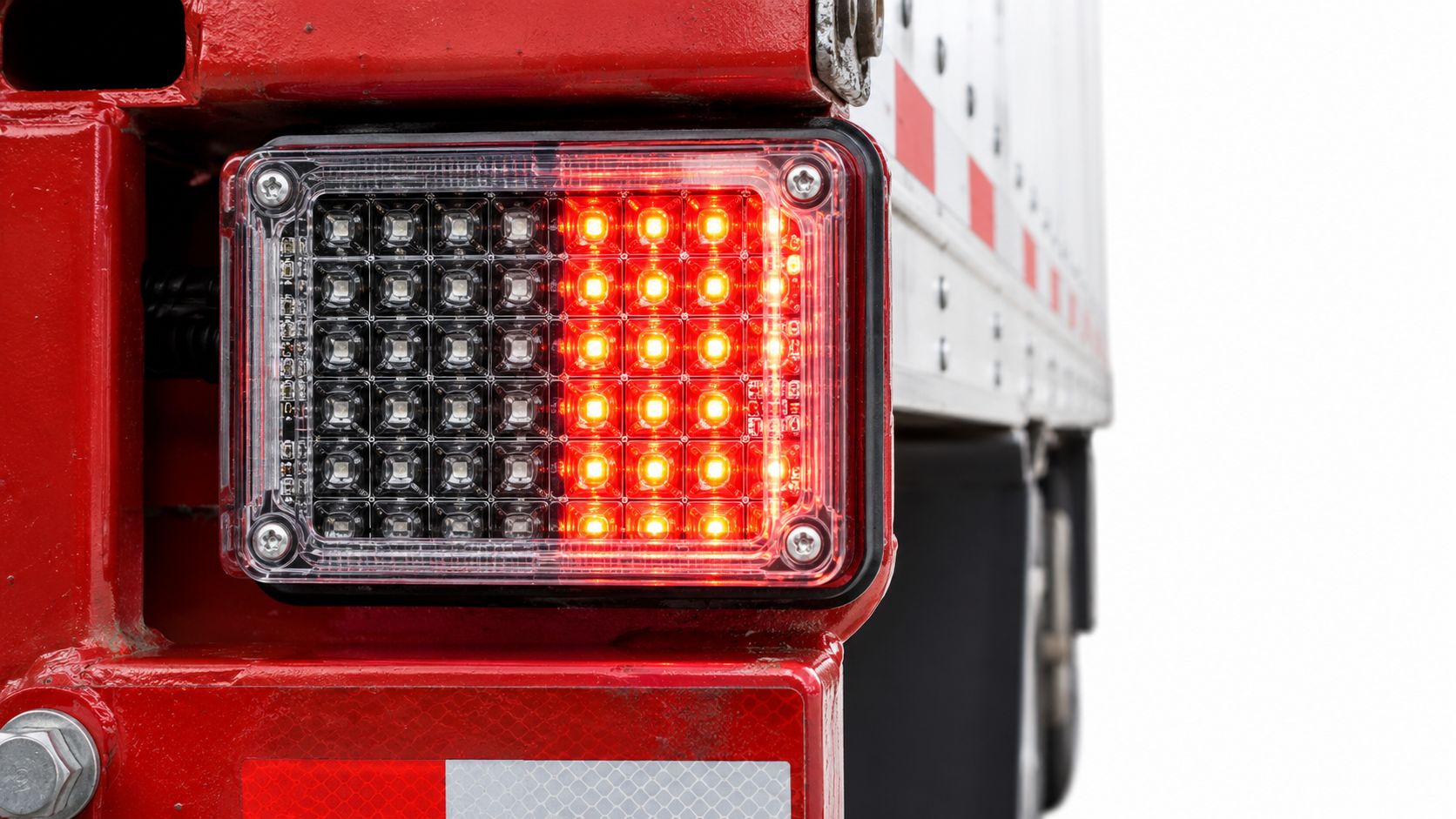 A close-up shot of a modern LED tail light on the back of a red semi-trailer.