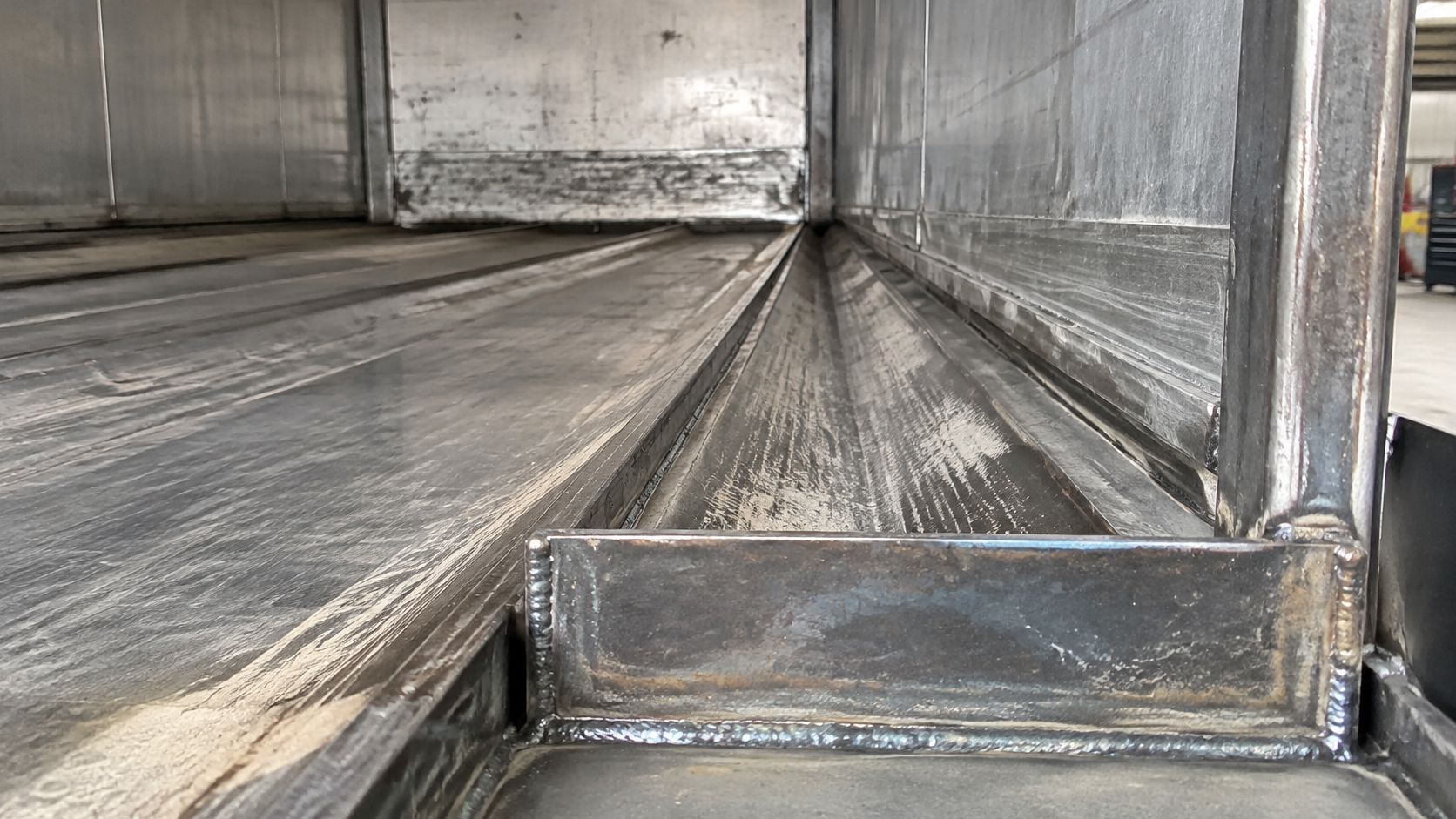 Close-up of a heavy-duty industrial trailer interior showing a newly welded metal walking floor slat mechanism.