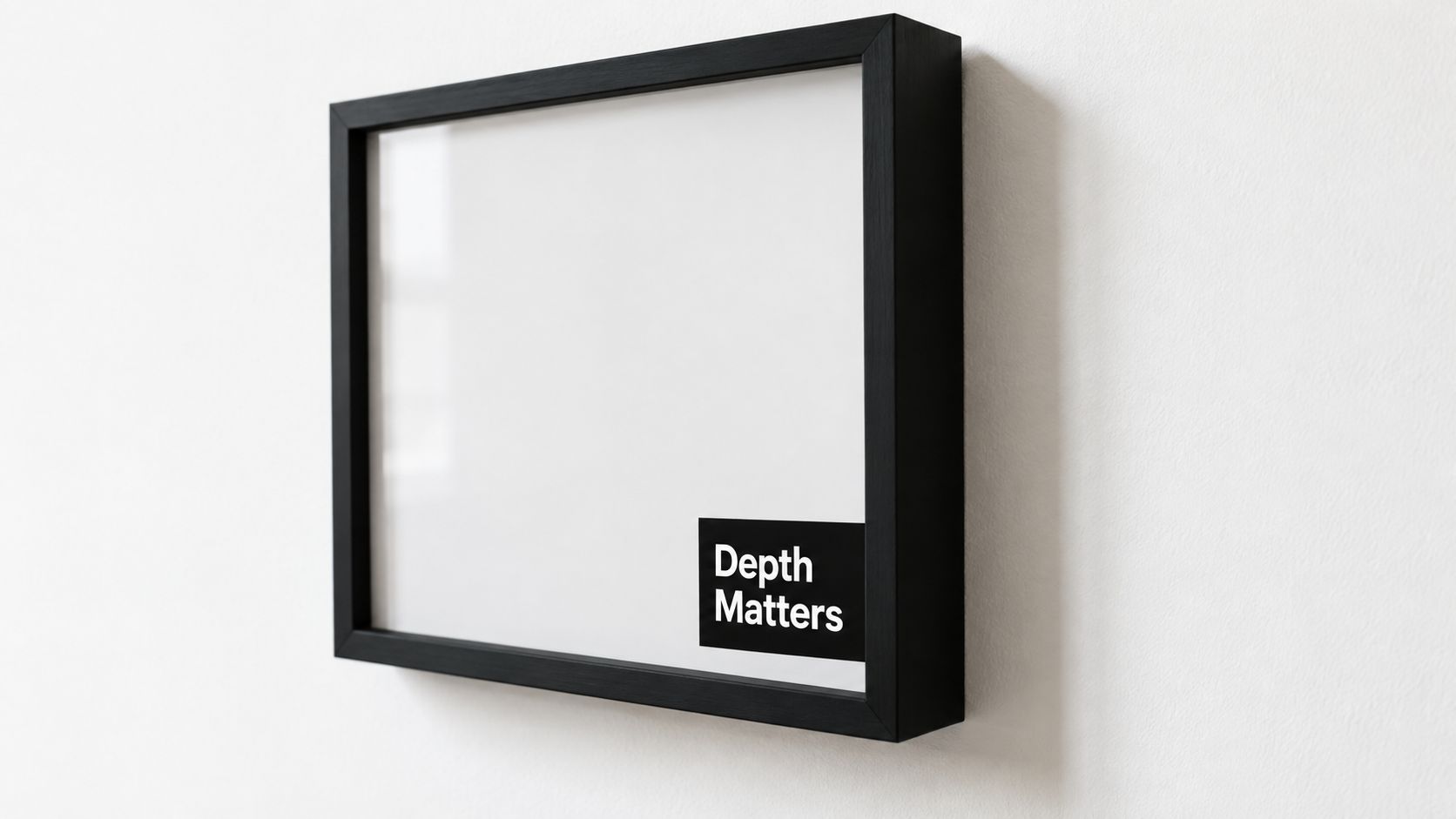 A modern black box frame with the text Depth Matters hanging on a plain white wall.