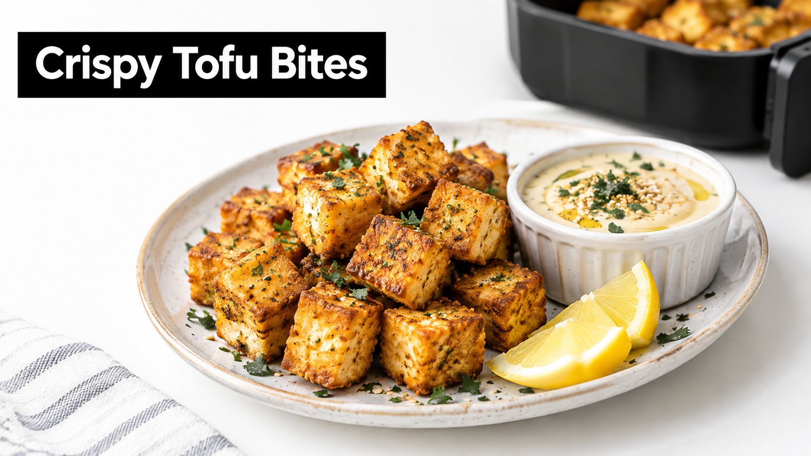 A plate of crispy tofu cubes served with a creamy dipping sauce and fresh lemon wedges.