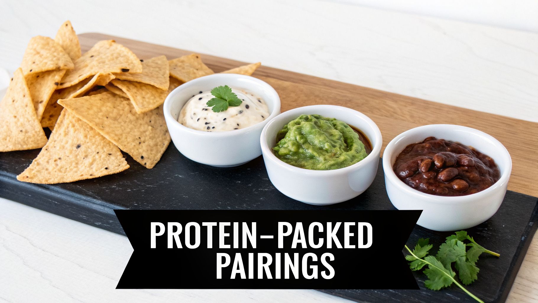 Tortilla chips with three protein-packed dips: creamy, guacamole, and black bean, on a serving board.