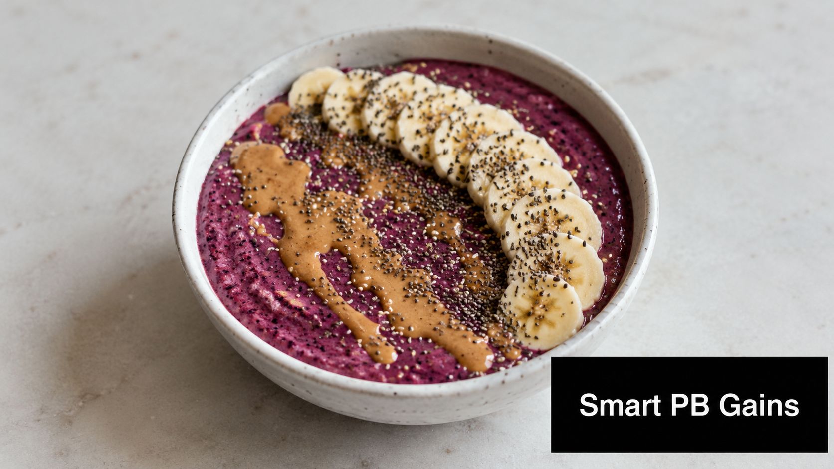 A creamy purple berry smoothie bowl topped with sliced bananas, chia seeds, and a drizzle of peanut butter.