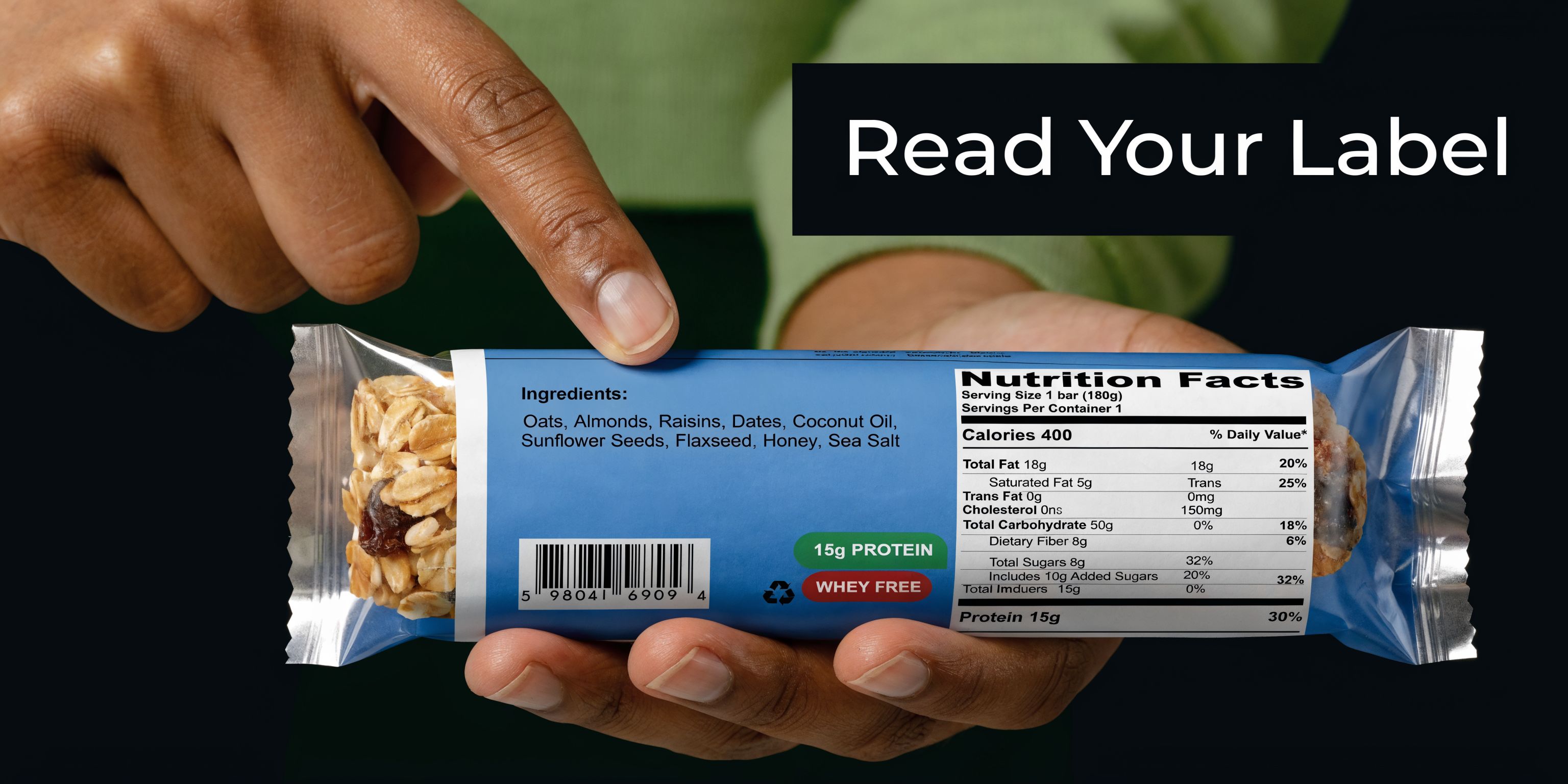 A person holds a protein bar packaging while pointing to the ingredients list on the label.