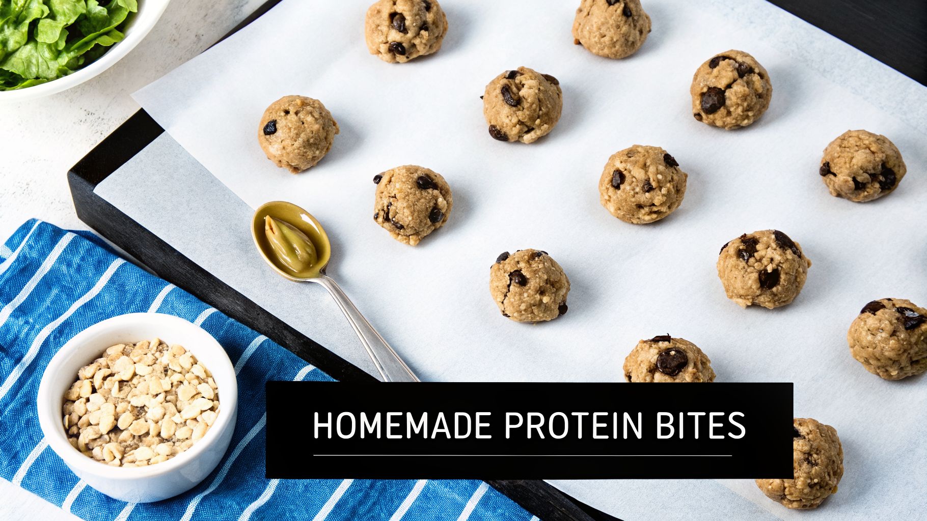 Homemade chocolate chip protein bites on parchment paper with a spoon of nut butter and chopped nuts.