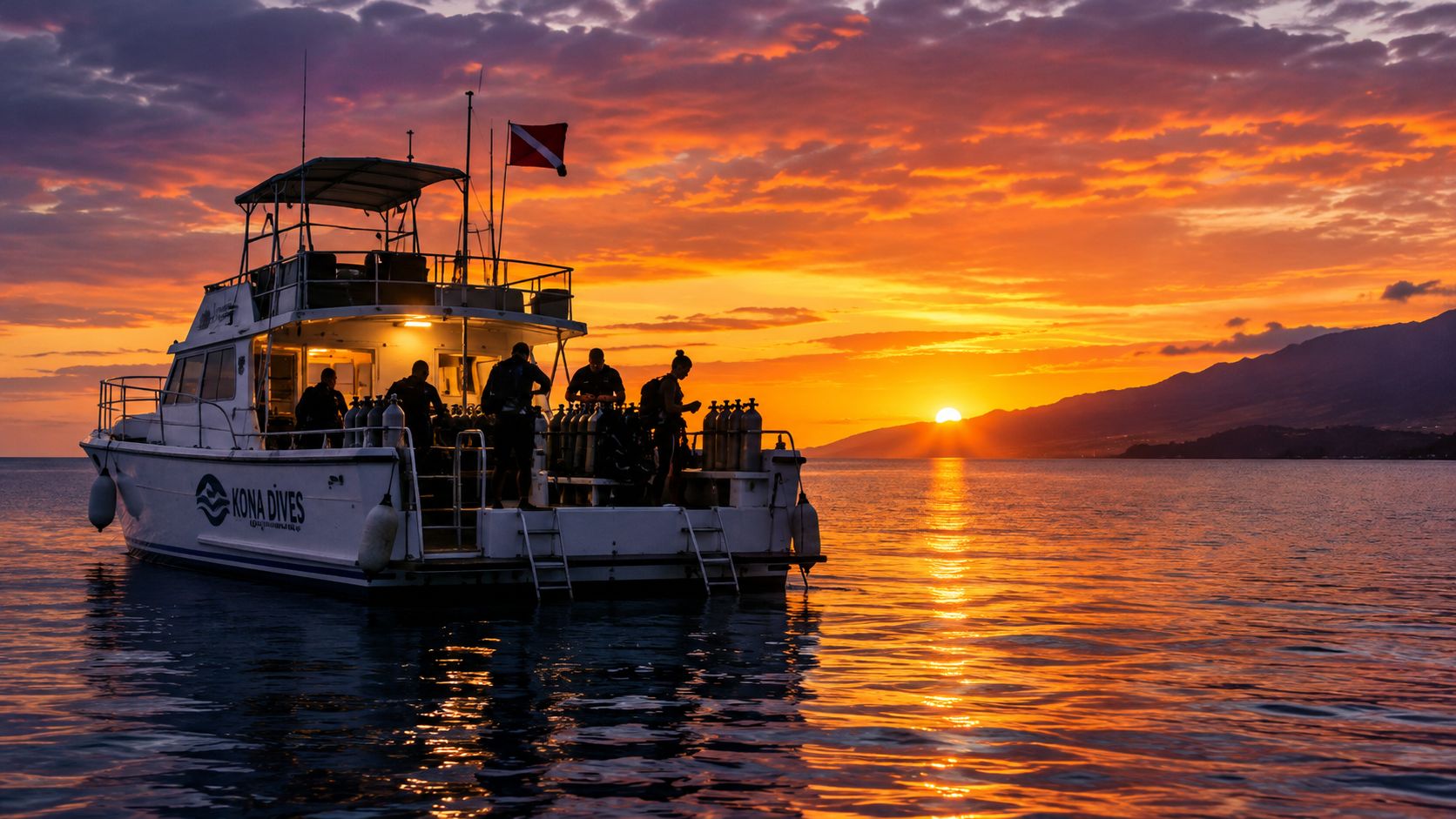 A Kona Dives boat filled with scuba divers silhouetted against a vibrant orange sunset over the ocean.