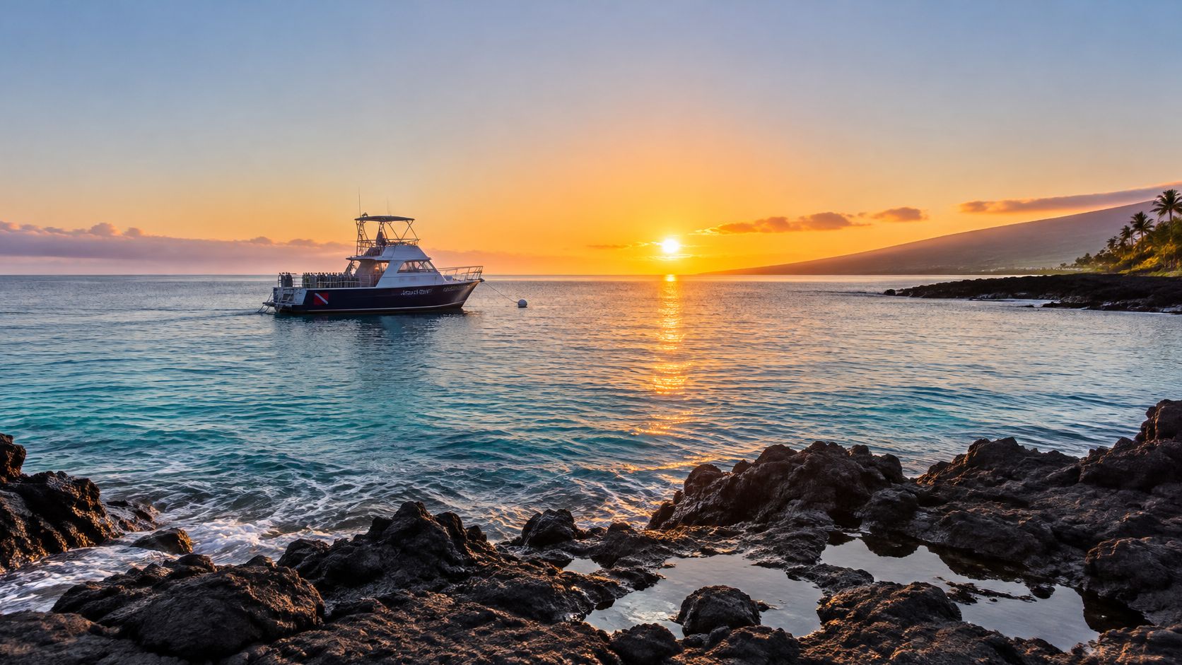 A scenic sunset over the ocean in Kona, Hawaii with a dive boat anchored near lava rocks.