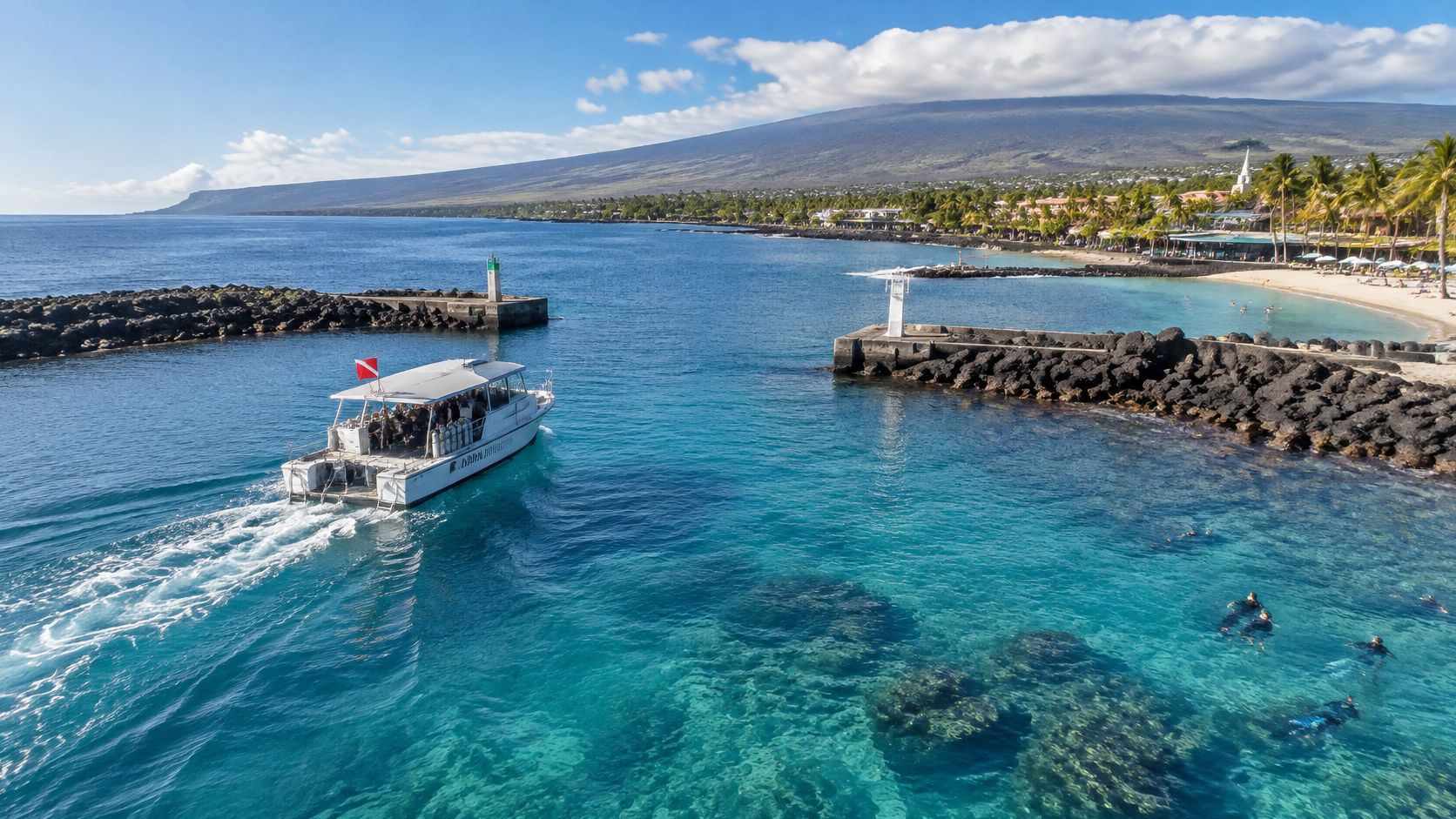 A dive boat leaves a sunny harbor in Kailua-Kona, Hawaii, past a lighthouse and snorkelers in clear water.