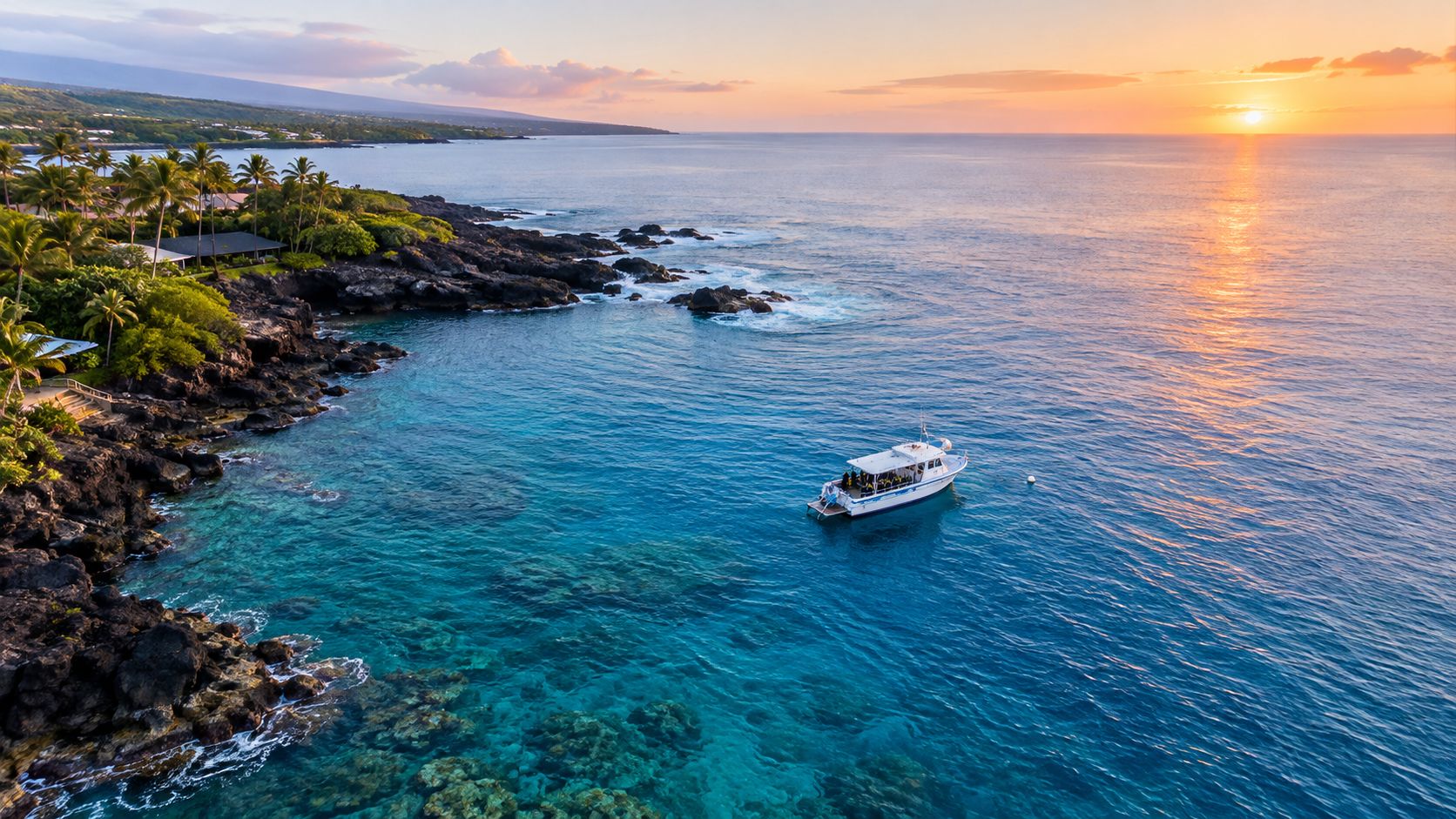 A boat anchored off the rocky Kona coastline during a scenic sunset over the Pacific Ocean.