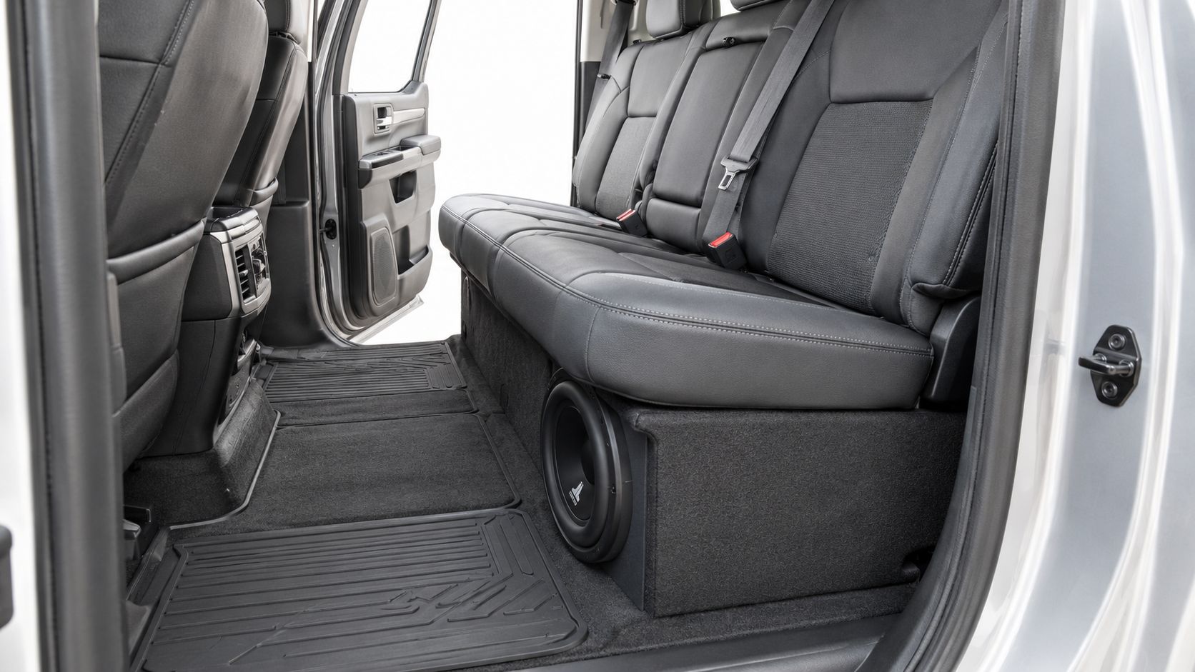 A custom 12-inch subwoofer box installed under the back seat of a modern pickup truck.