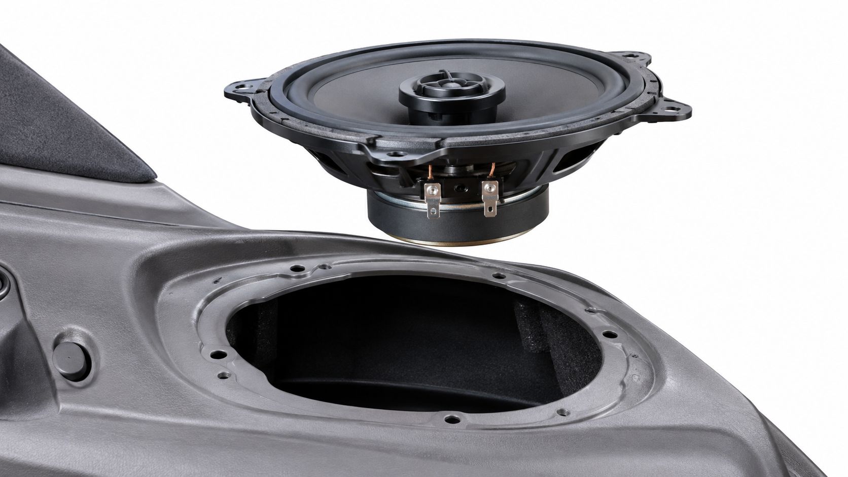 A car audio speaker being installed into a custom plastic speaker adapter mount for a vehicle door.