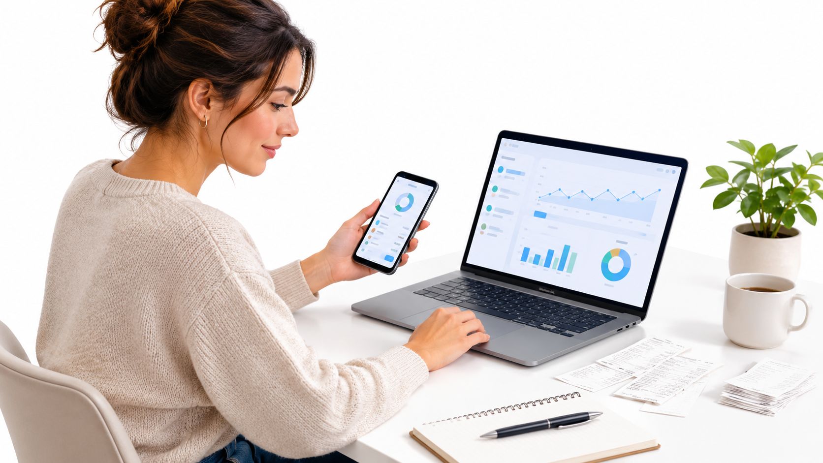 Eine junge Frau arbeitet an einem Laptop und Smartphone mit Finanzdiagrammen an einem Schreibtisch.