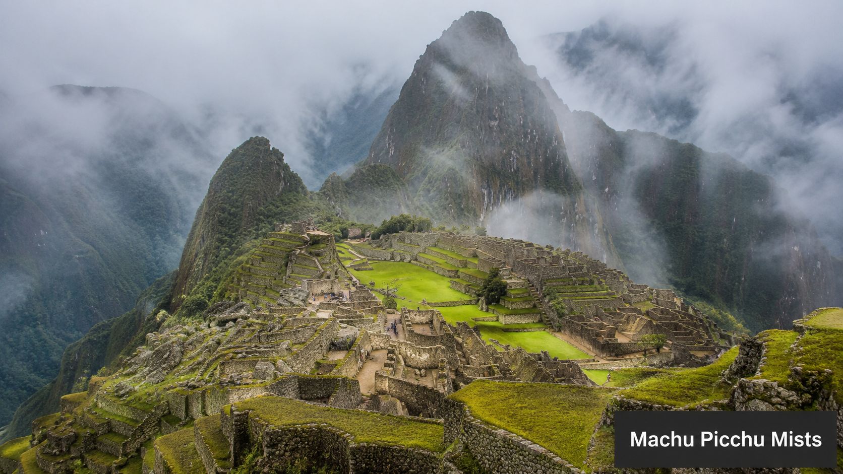 An aerial view of the ancient Incan citadel Machu Picchu surrounded by misty mountains during the rainy season.