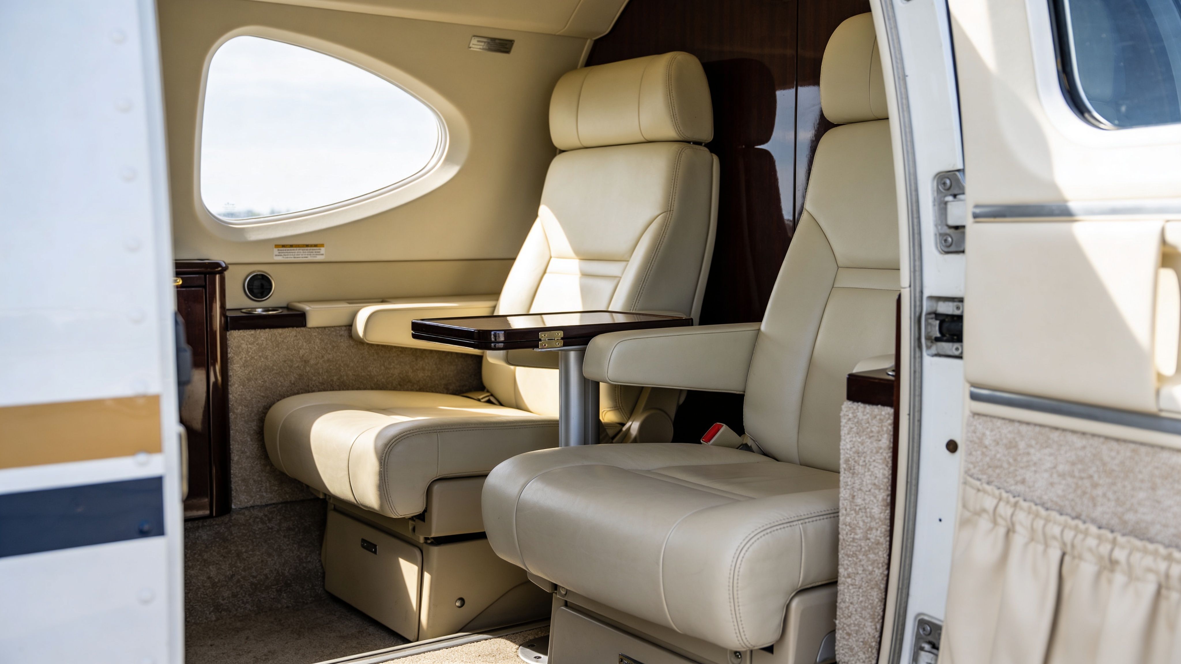 Luxurious beige leather passenger seats inside the cabin of a small private business aircraft.