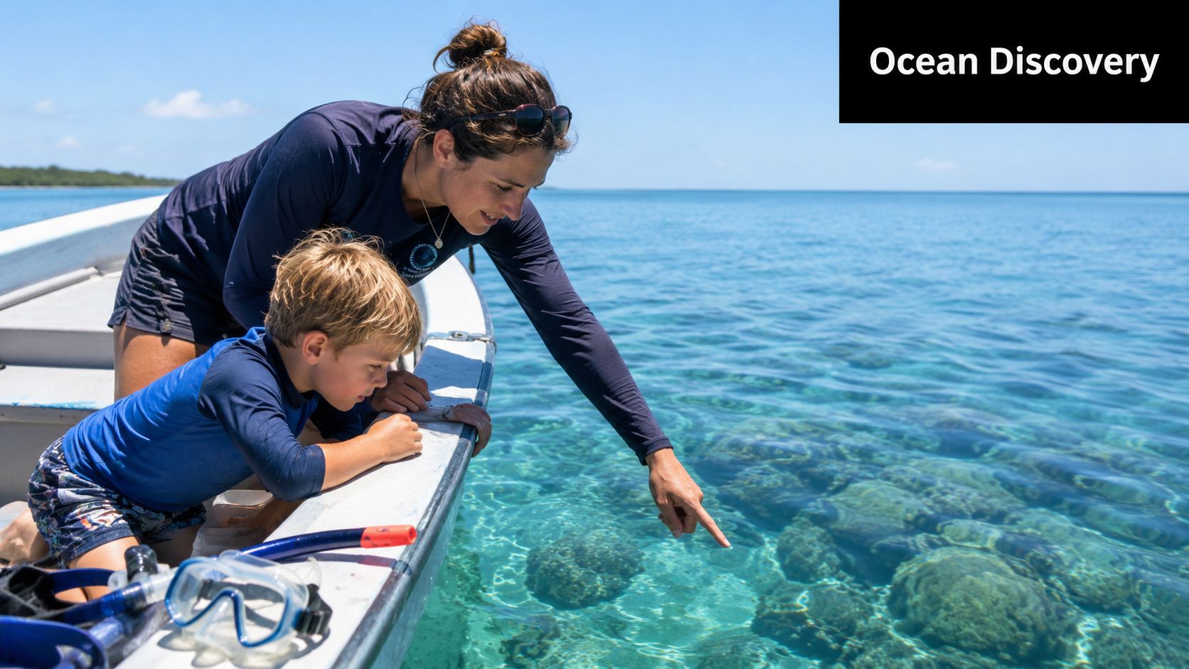 A woman and a young boy looking at coral reefs while on a boat in clear water.