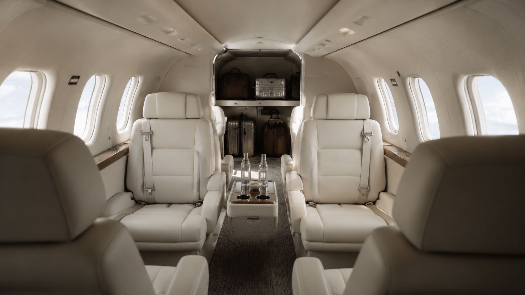 The luxurious interior of a small private jet featuring cream leather seats and elegant cabin details.