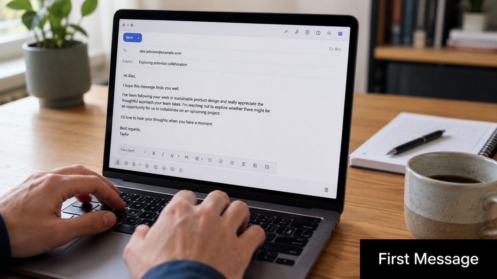 A person writing a professional email about potential collaboration on a laptop at a wooden desk.